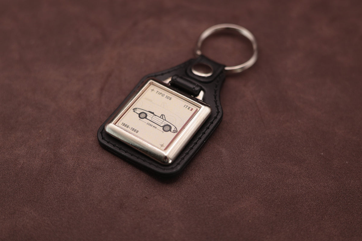 Alfa Romeo Spider 105 Register Series keyring angled with the split ring at upper right and ivory vehicle artwork visible