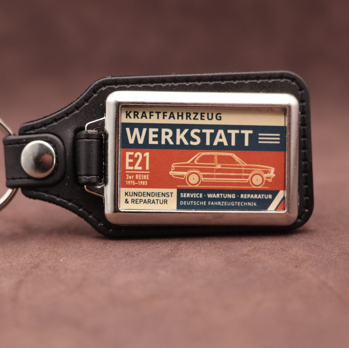 BMW E21 Werkstatt keyring with cream, dark blue and rust red workshop lettering and vehicle illustration
