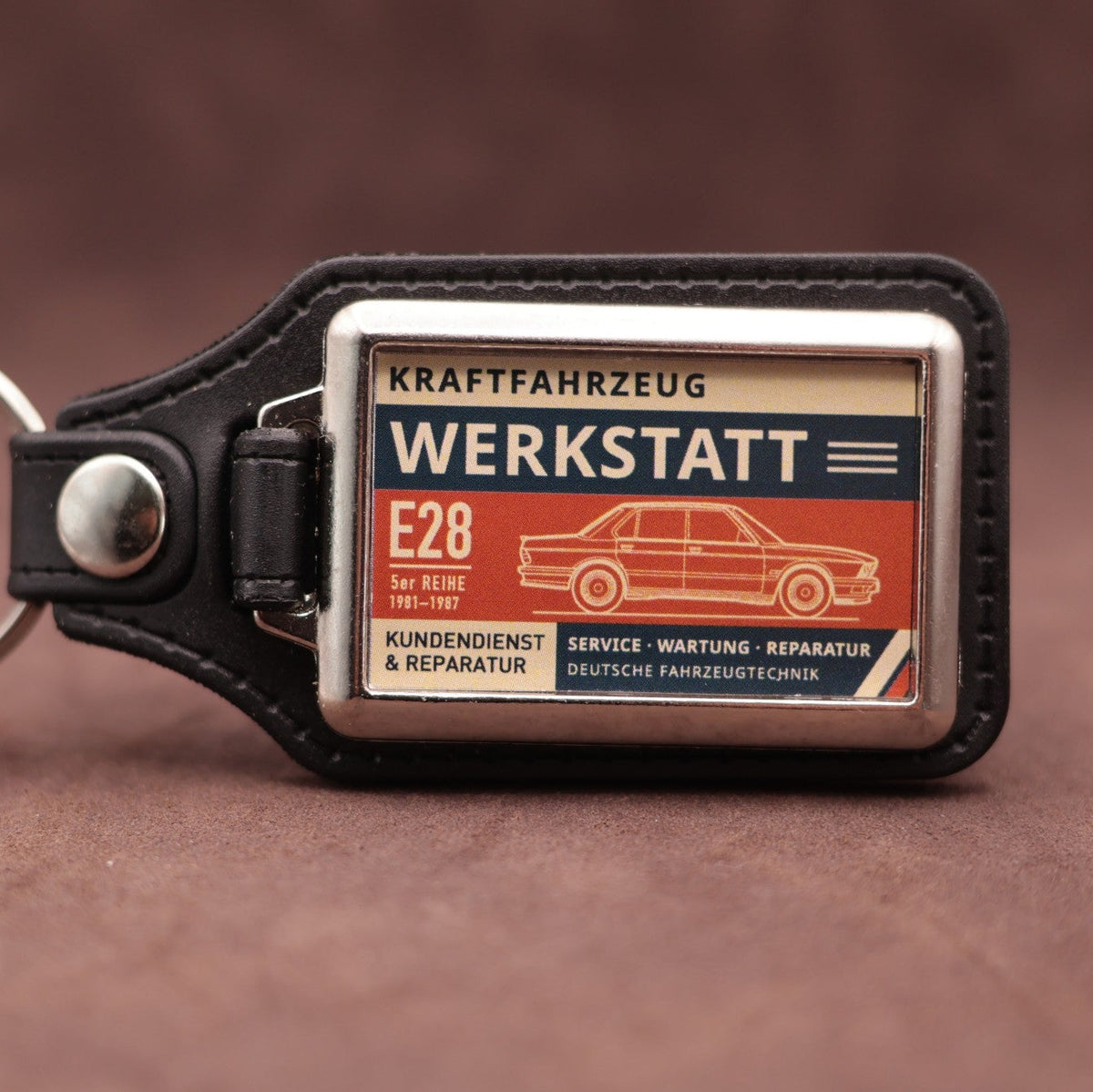 BMW E28 Werkstatt keyring with cream, dark blue and rust red workshop lettering and vehicle illustration