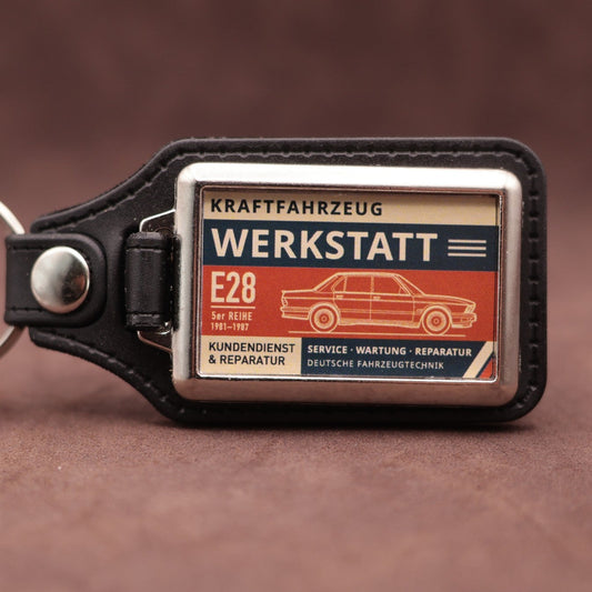 BMW E28 Werkstatt keyring with cream, dark blue and rust red workshop lettering and vehicle illustration