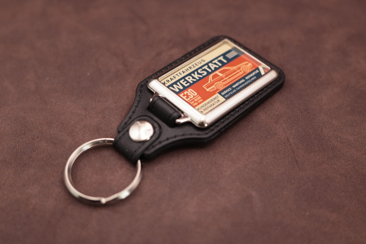 BMW E30 Werkstatt keyring angled with the split ring at upper left, showing the printed label and chromed frame