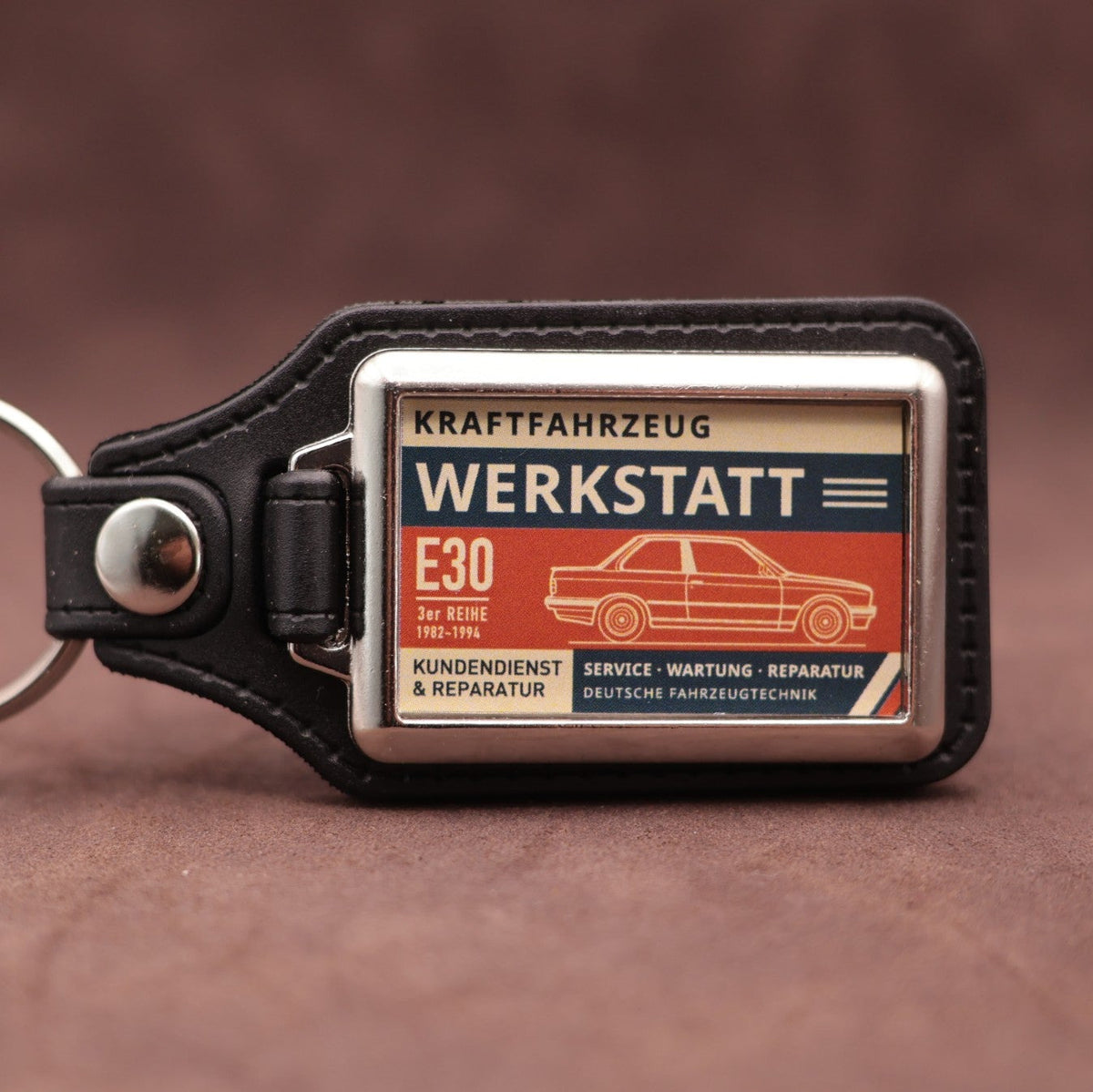 BMW E30 Werkstatt keyring with cream, dark blue and rust red workshop lettering and vehicle illustration