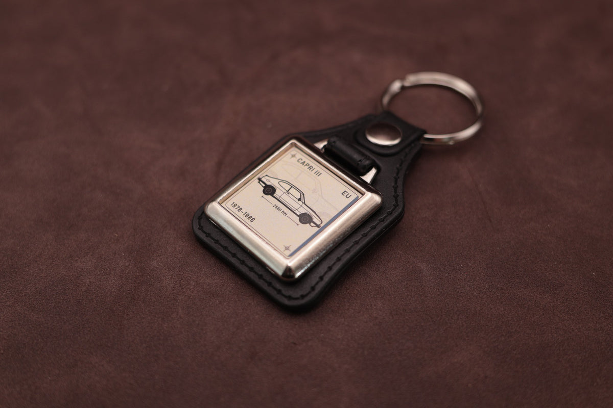 Ford Capri Mk3 Register Series keyring angled with the split ring at upper right and ivory vehicle artwork visible