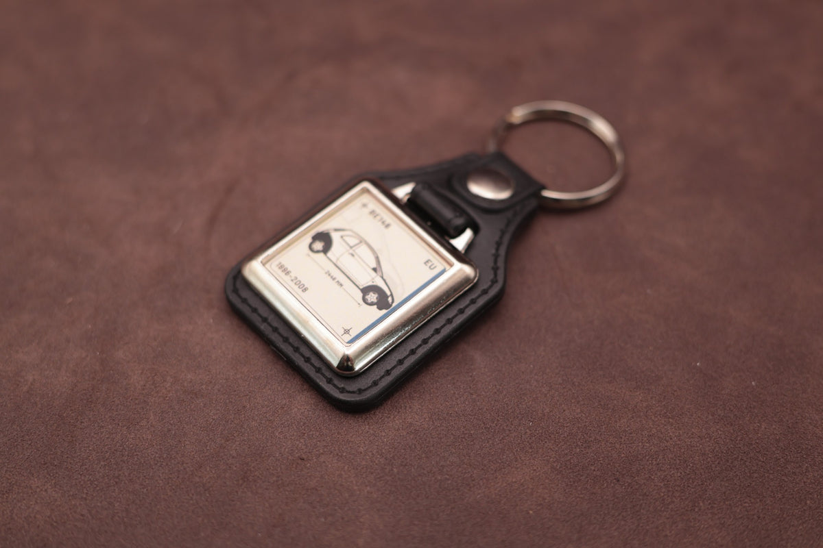 Ford Ka Mk1 Register Series keyring angled with the split ring at upper right and ivory vehicle artwork visible