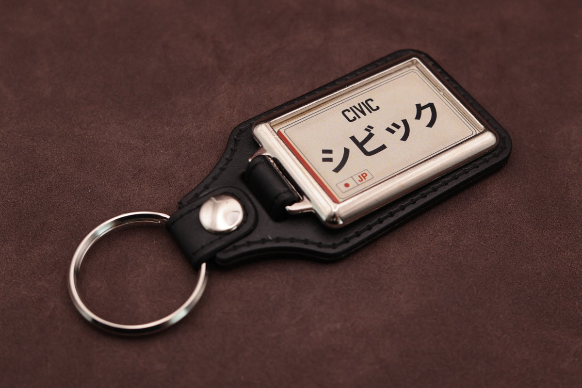 Honda Civic Katakana keyring angled with the split ring at lower left, showing the cream insert and black leatherette fob