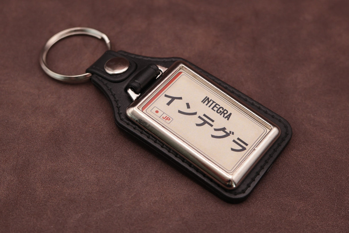 Honda Integra Katakana keyring angled with the split ring at upper left, showing the printed insert and chromed frame