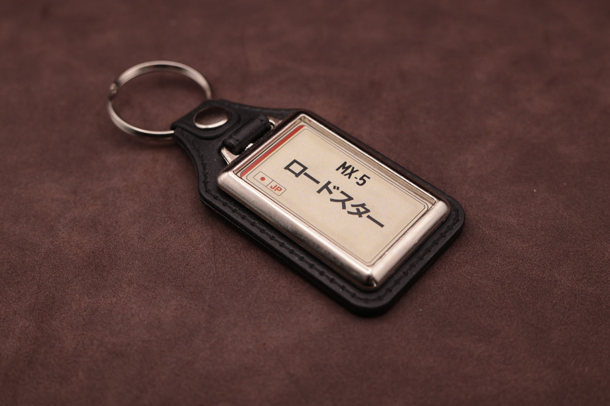 Mazda MX-5 Katakana keyring angled with the split ring at upper left, showing the printed insert and chromed frame