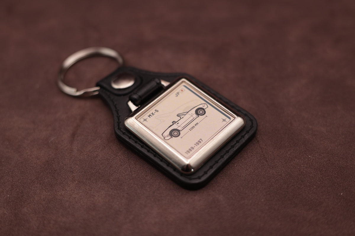 Mazda MX-5 NA Register Series keyring angled with the split ring at upper left, showing the square chromed frame