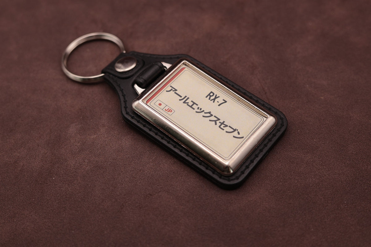 Mazda RX-7 Katakana keyring angled with the split ring at upper left, showing the printed insert and chromed frame