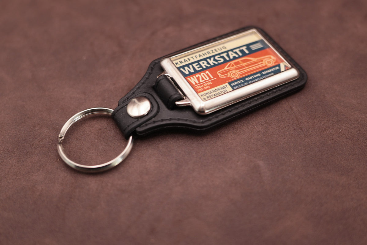 Mercedes-Benz W201 190 Werkstatt keyring angled with the split ring at upper left, showing the printed label and chromed frame