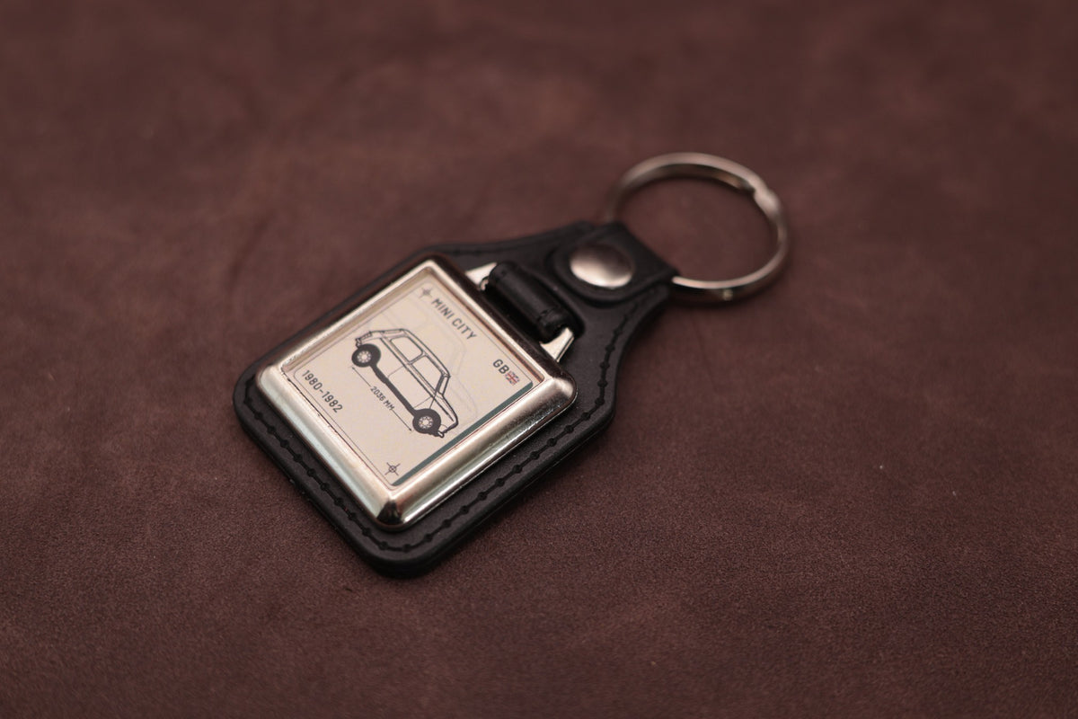 Mini City Register Series keyring angled with the split ring at upper right and ivory vehicle artwork visible