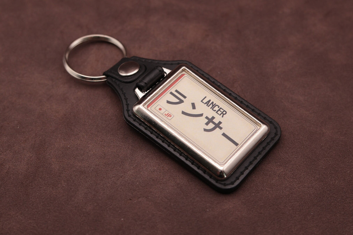 Mitsubishi Lancer Katakana keyring angled with the split ring at upper left, showing the printed insert and chromed frame