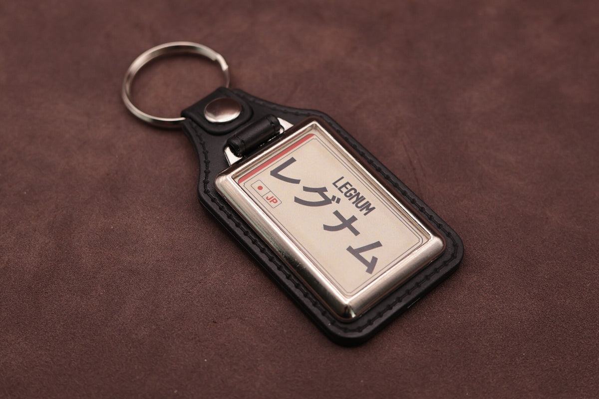 Mitsubishi Legnum Katakana keyring angled with the split ring at upper left, showing the printed insert and chromed frame