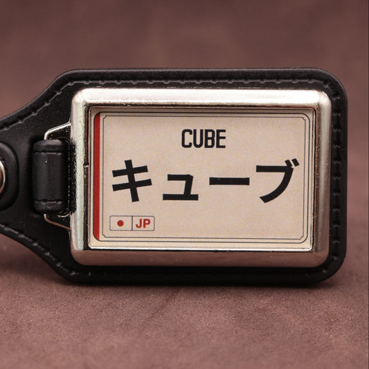 Nissan Cube keyring with Japanese katakana and model lettering on a cream plate-inspired insert
