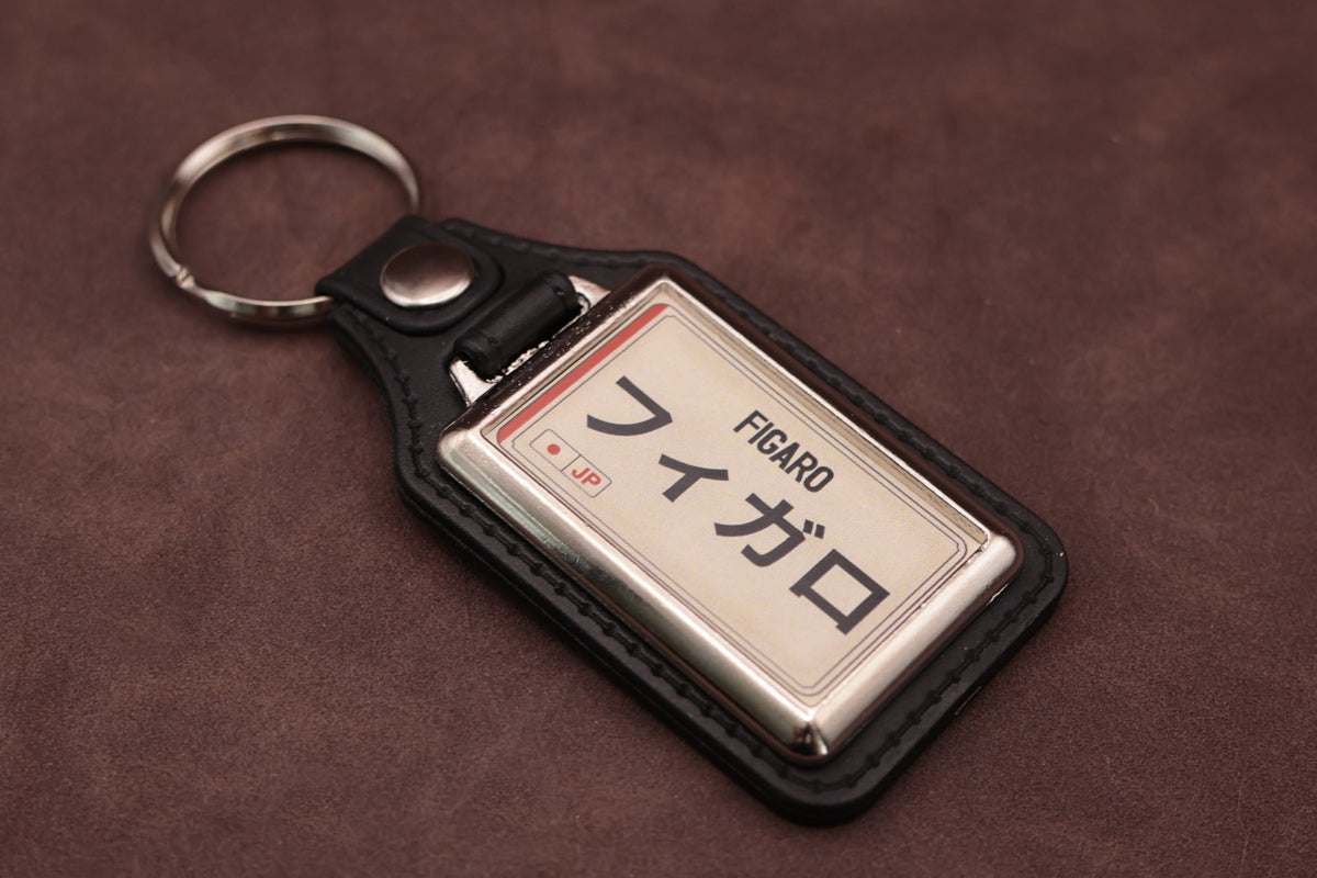 Nissan Figaro Katakana keyring angled with the split ring at upper left, showing the printed insert and chromed frame