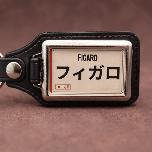 Nissan Figaro keyring with Japanese katakana and model lettering on a cream plate-inspired insert
