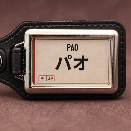 Nissan Pao keyring with Japanese katakana and model lettering on a cream plate-inspired insert