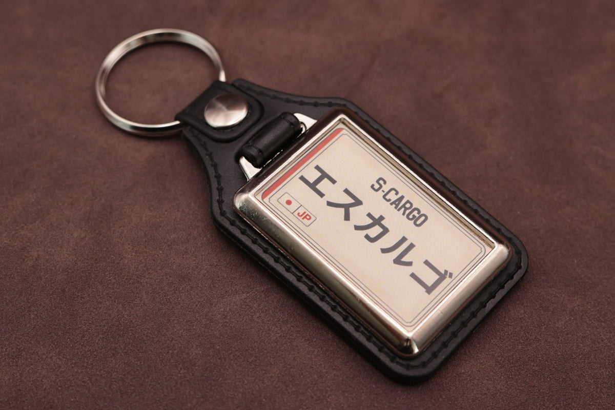 Nissan S-Cargo Katakana keyring angled with the split ring at upper left, showing the printed insert and chromed frame