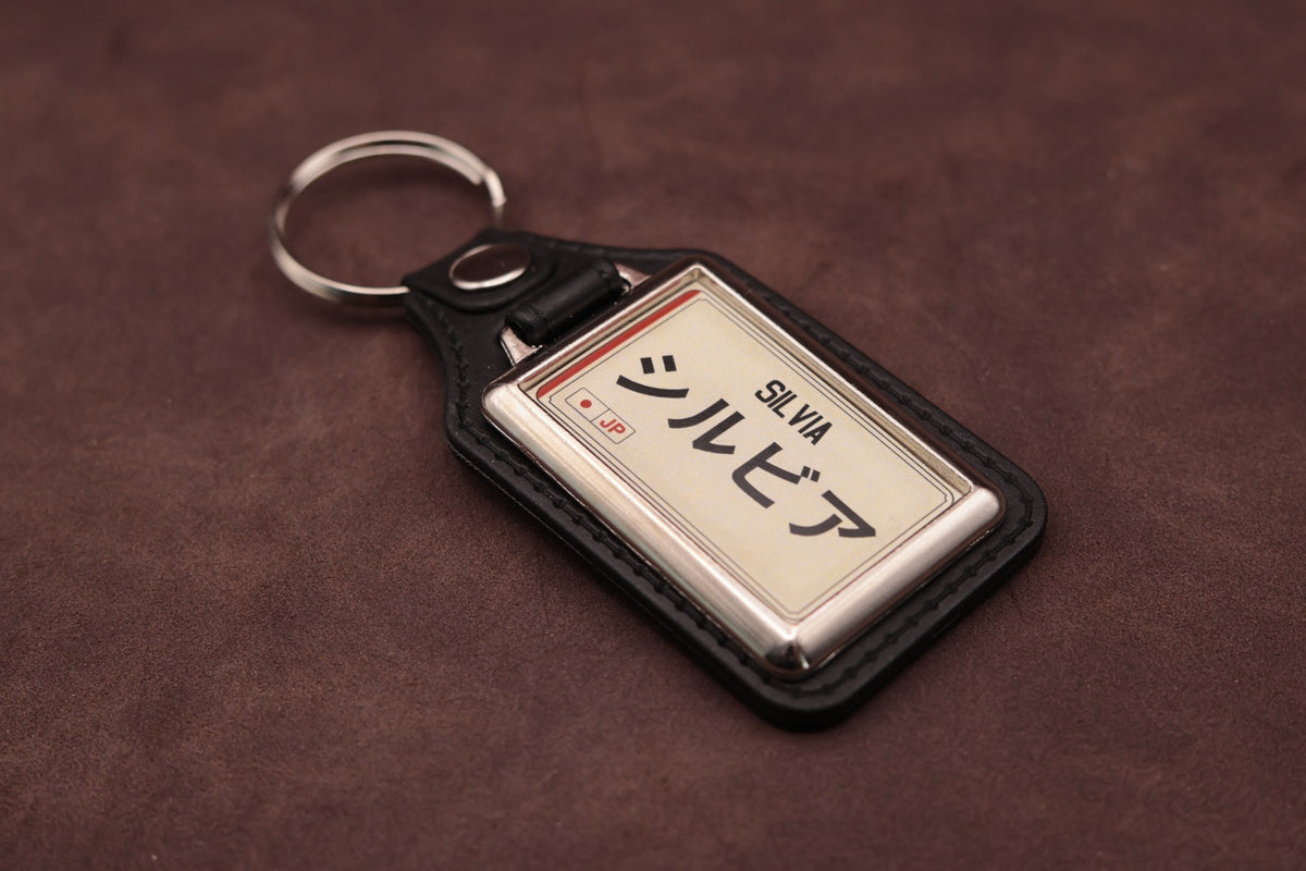 Nissan Silvia Katakana keyring angled with the split ring at upper left, showing the printed insert and chromed frame