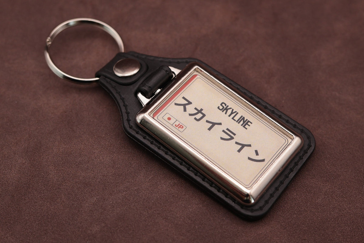 Nissan Skyline Katakana keyring angled with the split ring at upper left, showing the printed insert and chromed frame