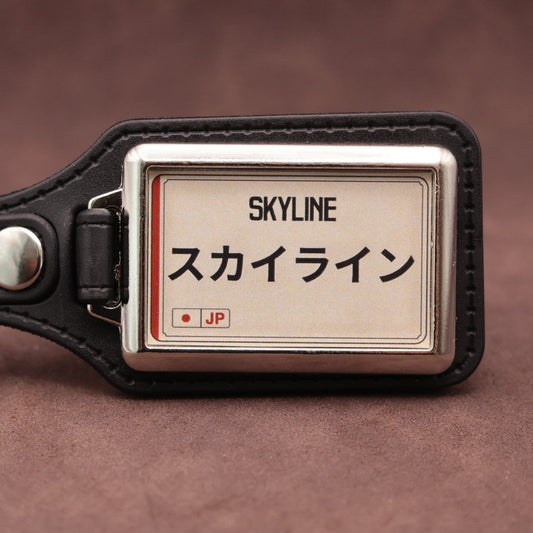 Nissan Skyline keyring with Japanese katakana and model lettering on a cream plate-inspired insert