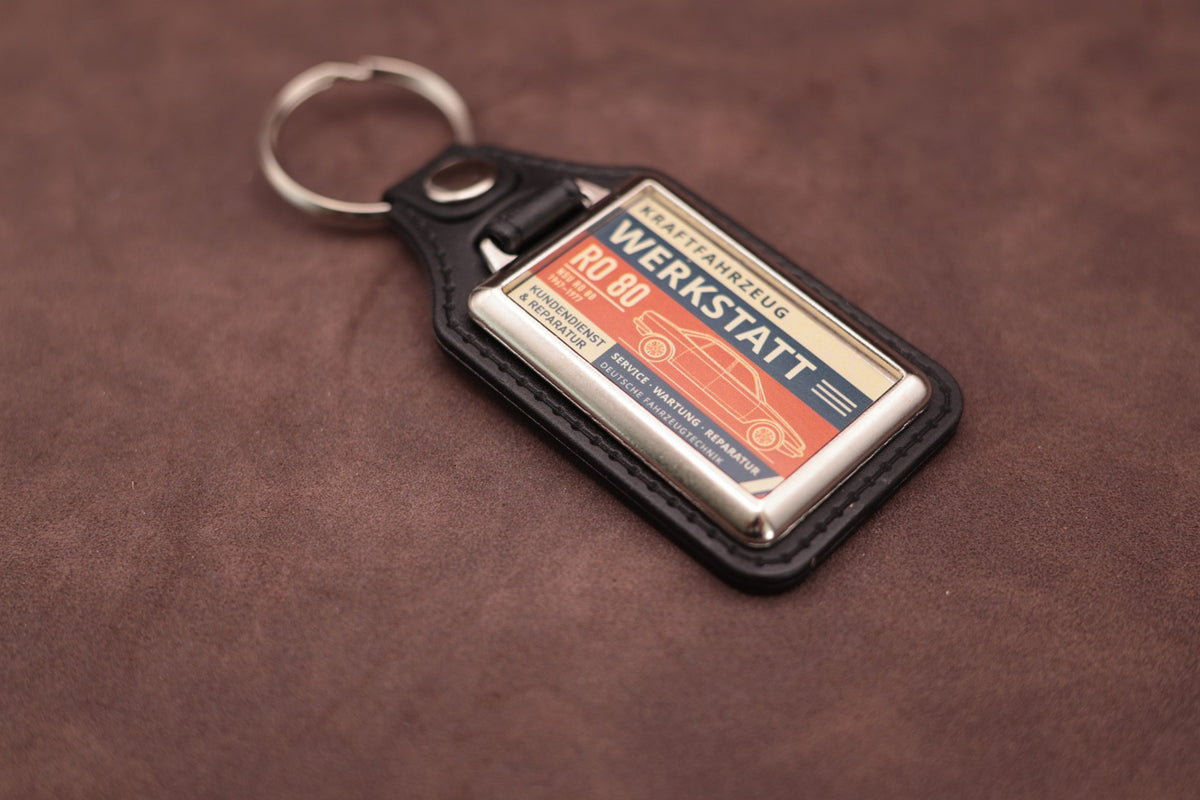 NSU Ro80 Werkstatt keyring angled with the split ring at lower left, showing the printed label and black leatherette fob