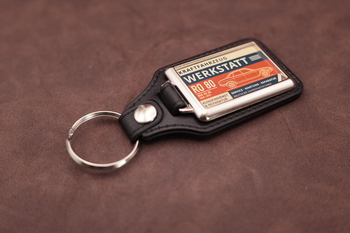 NSU Ro80 Werkstatt keyring angled with the split ring at upper left, showing the printed label and chromed frame