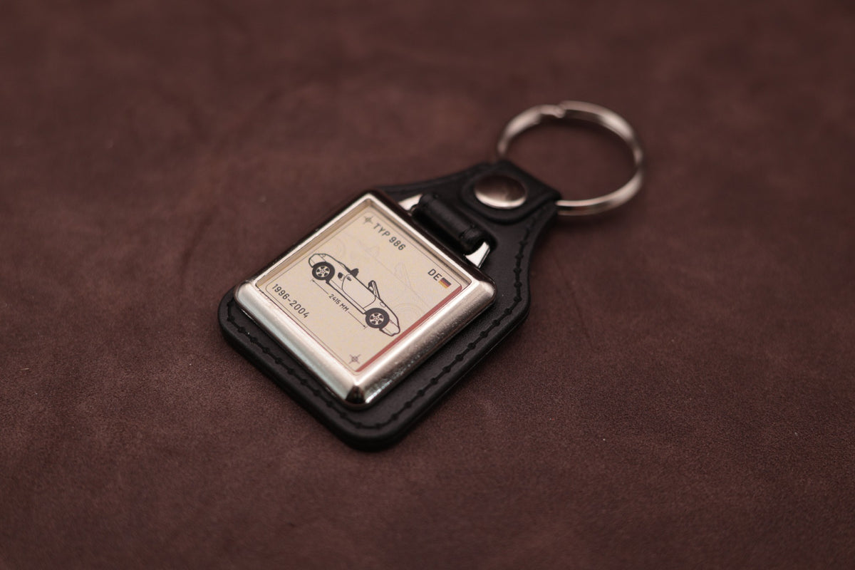 Porsche Boxster 986 Register Series keyring angled with the split ring at upper right and ivory vehicle artwork visible