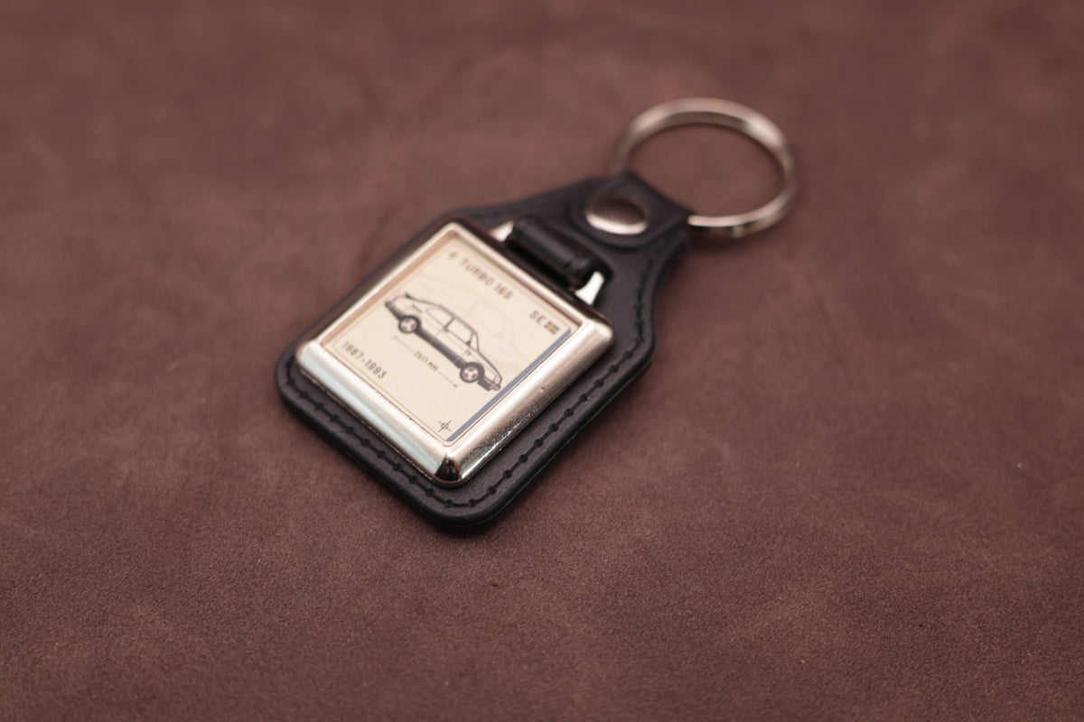 Saab 900 Turbo 16S Register Series keyring angled with the split ring at upper right and ivory vehicle artwork visible