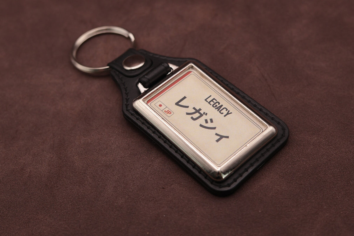Subaru Legacy Katakana keyring angled with the split ring at upper left, showing the printed insert and chromed frame