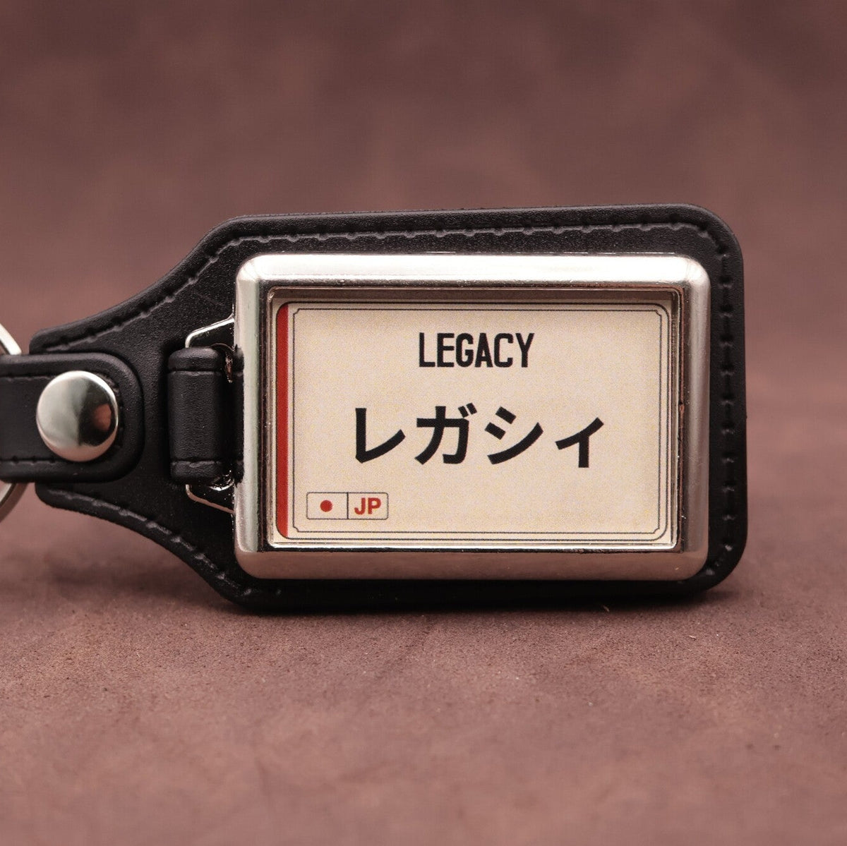 Subaru Legacy keyring with Japanese katakana and model lettering on a cream plate-inspired insert