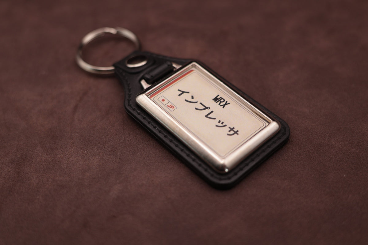 Subaru WRX Katakana keyring angled with the split ring at upper left, showing the printed insert and chromed frame