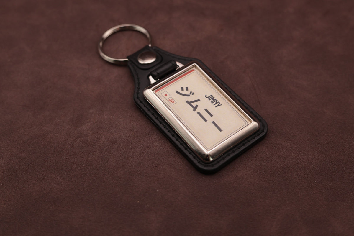Suzuki Jimny Katakana keyring angled with the split ring at upper left, showing the printed insert and chromed frame