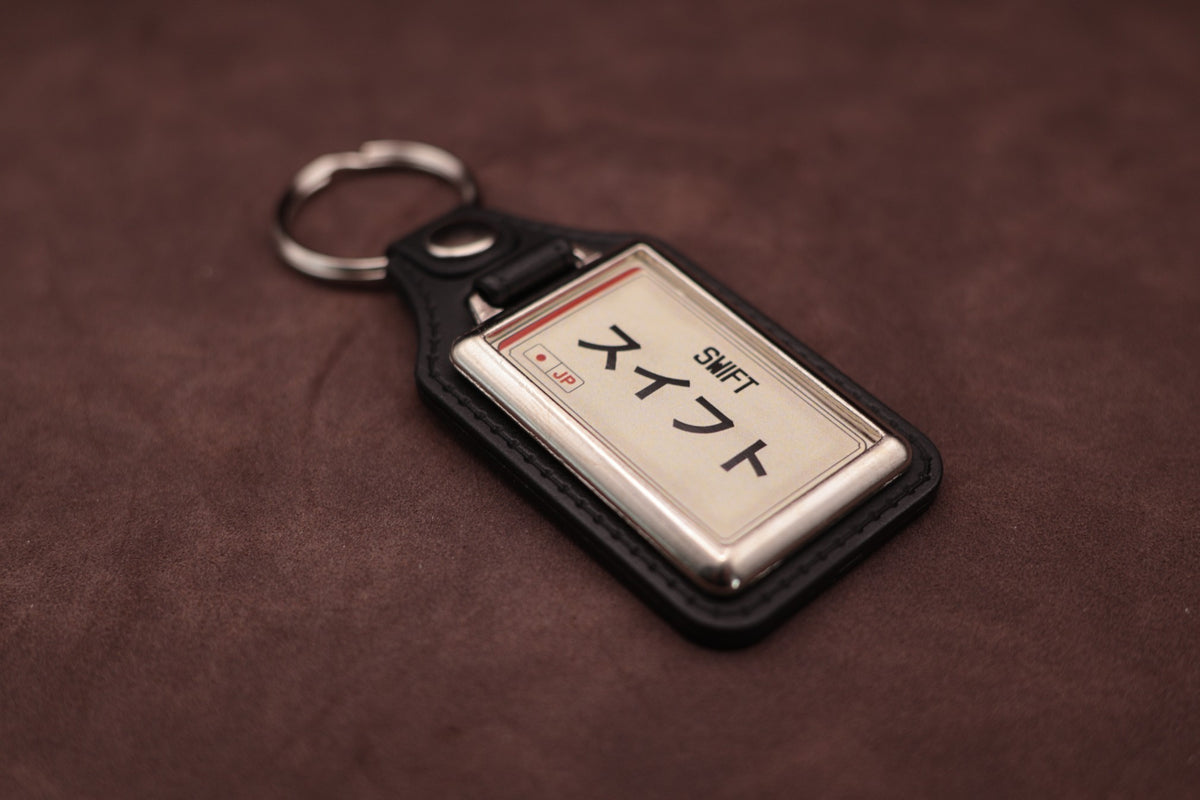 Suzuki Swift Katakana keyring angled with the split ring at upper left, showing the printed insert and chromed frame