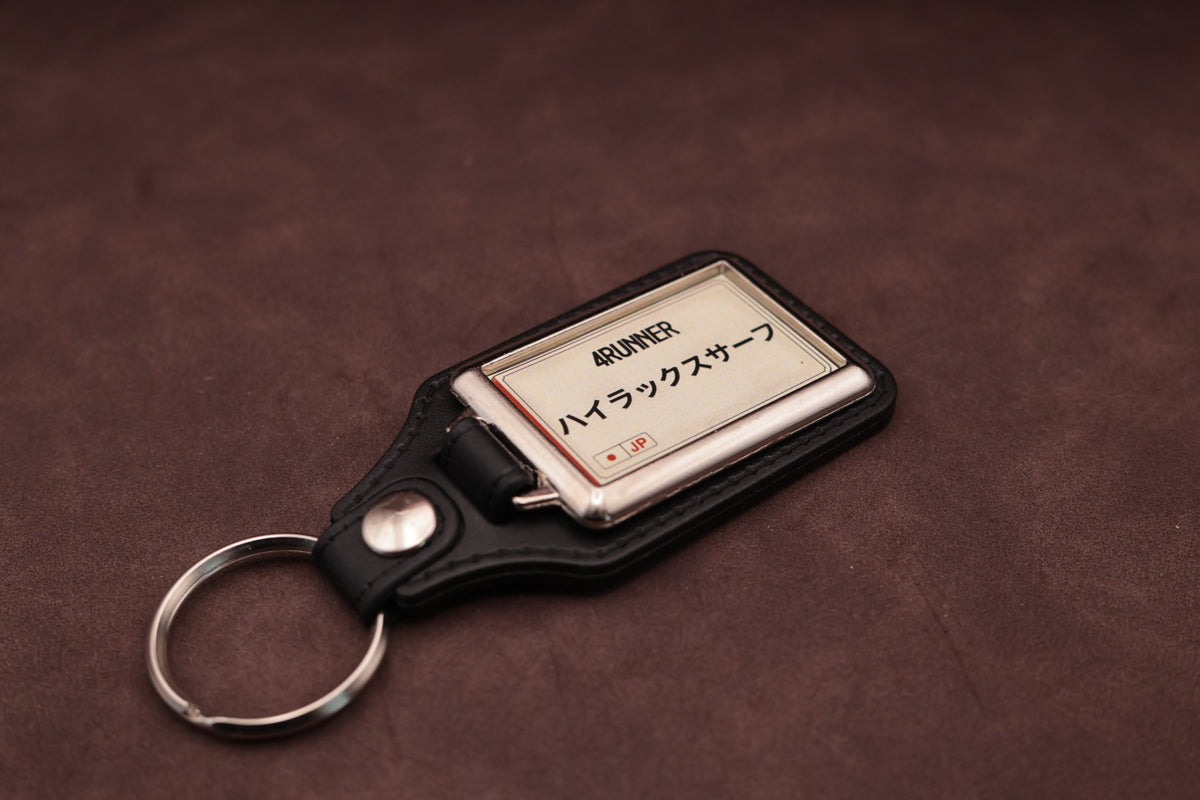 Toyota 4Runner Katakana keyring angled with the split ring at lower left, showing the cream insert and black leatherette fob