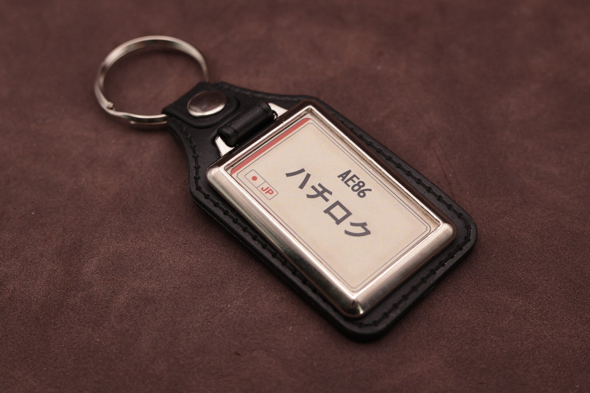 Toyota AE86 Katakana keyring angled with the split ring at upper left, showing the printed insert and chromed frame