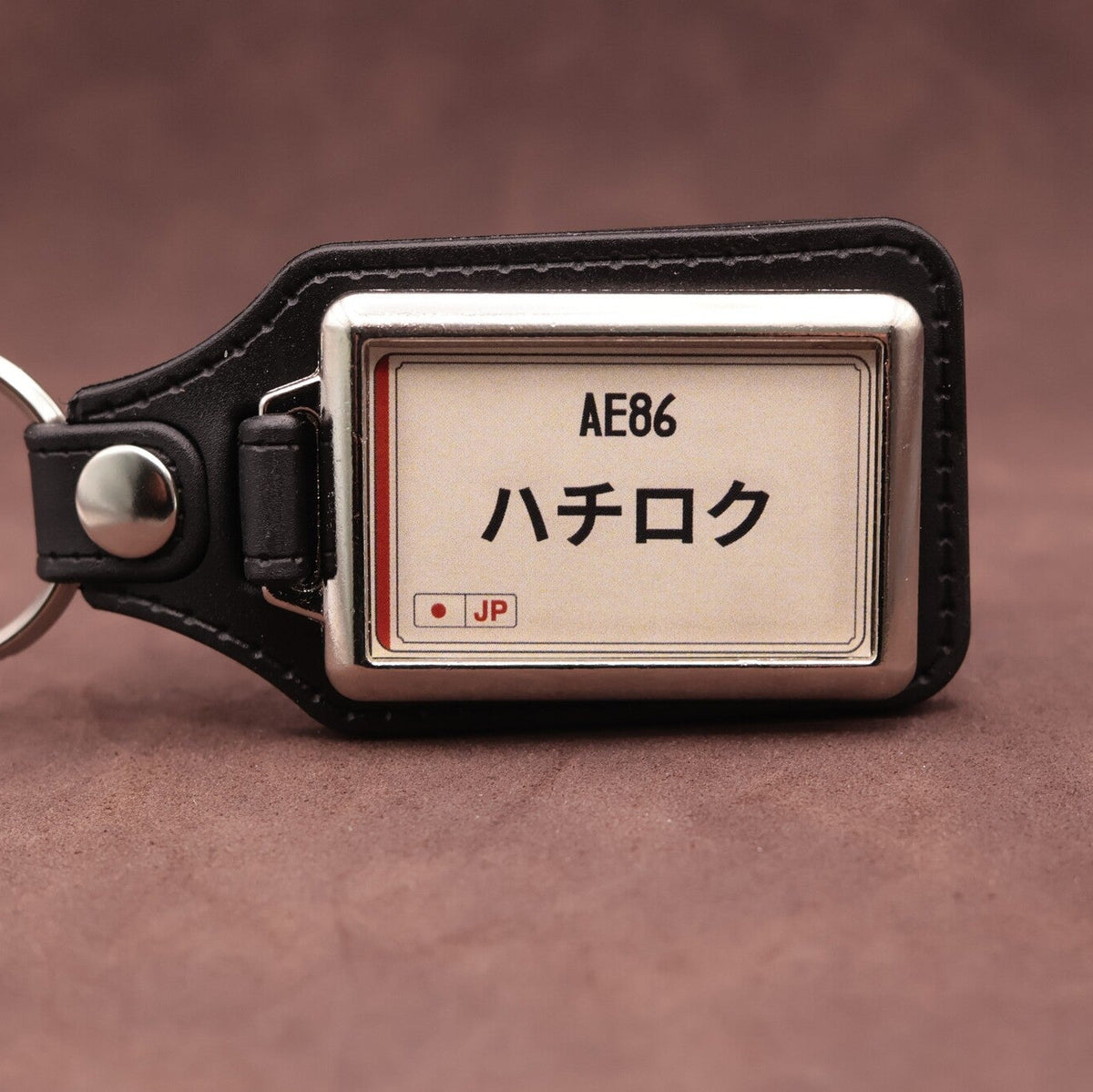Toyota AE86 keyring with Japanese katakana and model lettering on a cream plate-inspired insert