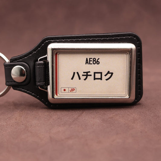 Toyota AE86 keyring with Japanese katakana and model lettering on a cream plate-inspired insert
