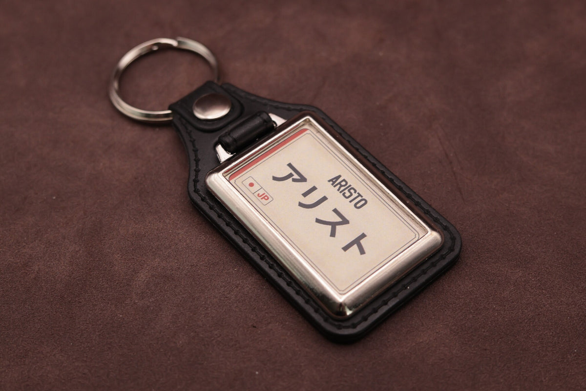 Toyota Aristo Katakana keyring angled with the split ring at upper left, showing the printed insert and chromed frame