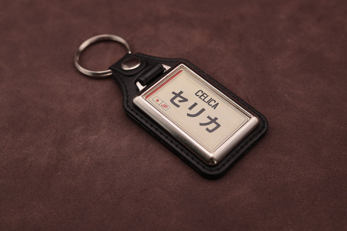 Toyota Celica Katakana keyring angled with the split ring at upper left, showing the printed insert and chromed frame