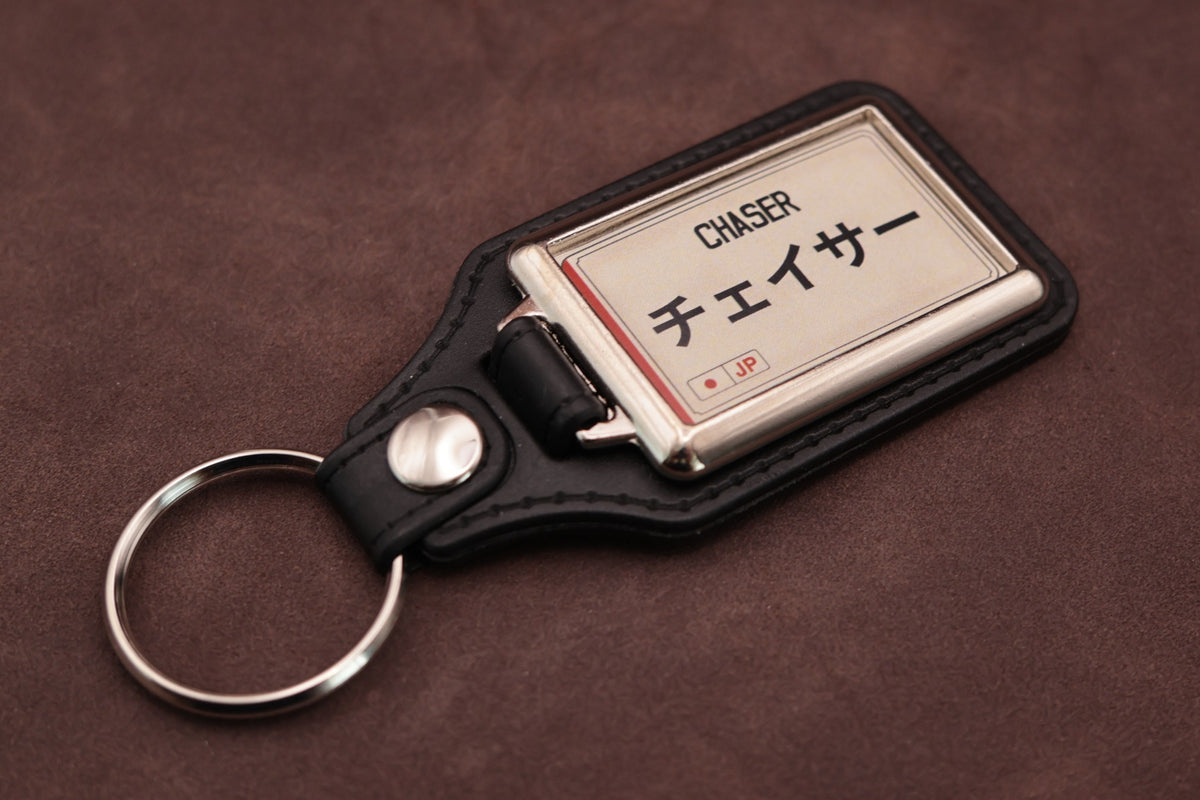 Toyota Chaser Katakana keyring angled with the split ring at lower left, showing the cream insert and black leatherette fob