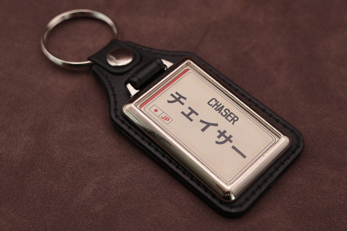 Toyota Chaser Katakana keyring angled with the split ring at upper left, showing the printed insert and chromed frame