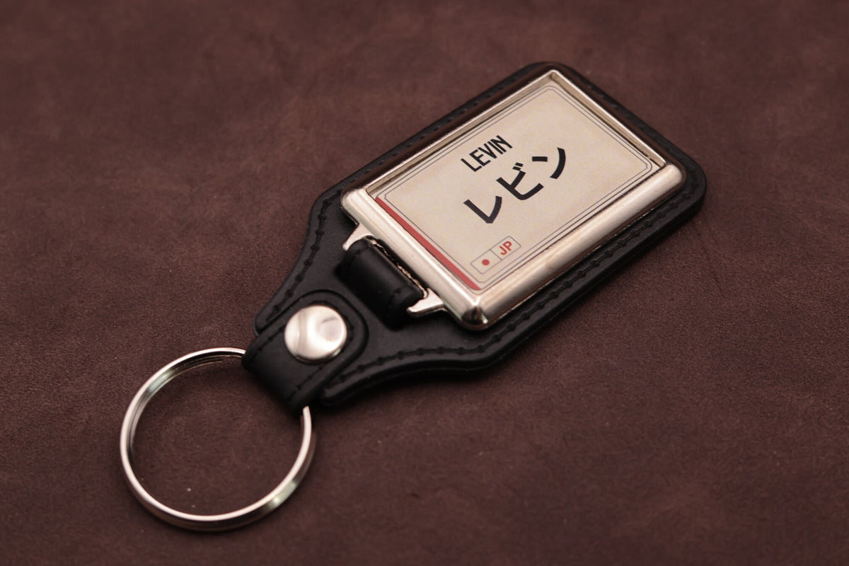 Toyota Levin Katakana keyring angled with the split ring at lower left, showing the cream insert and black leatherette fob