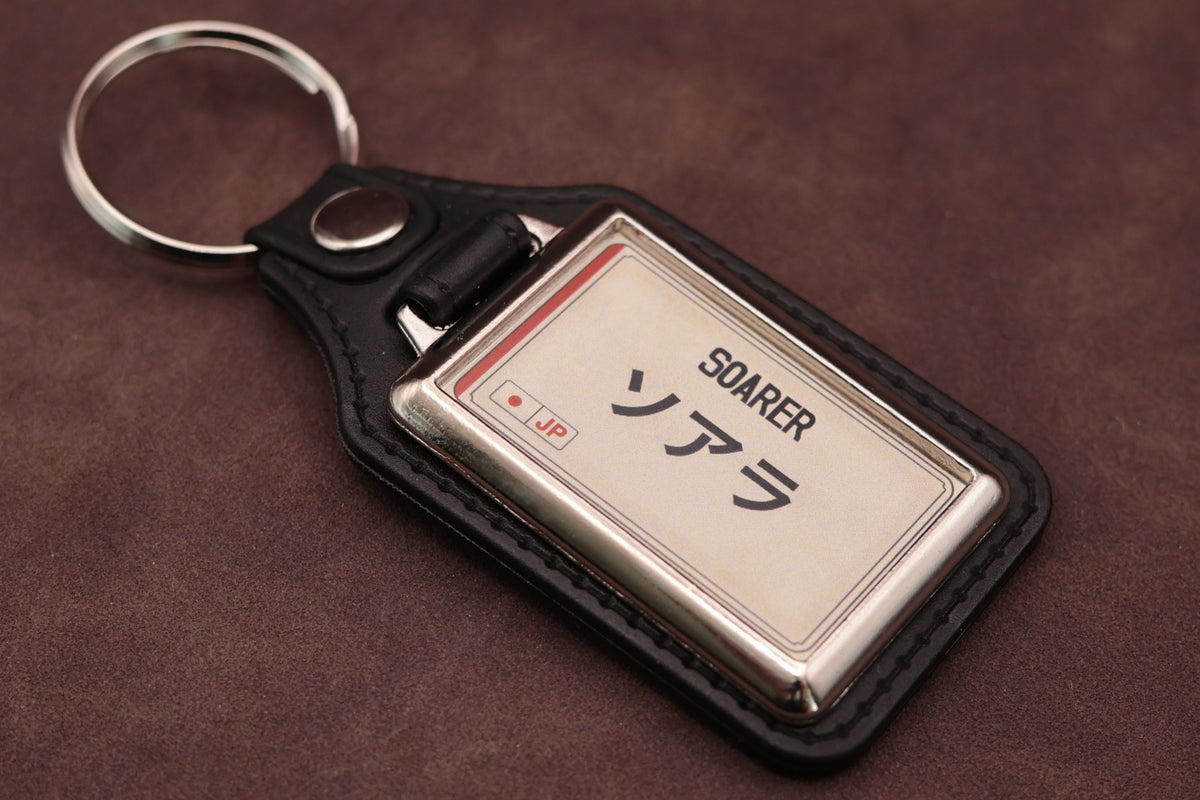 Toyota Soarer Katakana keyring angled with the split ring at upper left, showing the printed insert and chromed frame