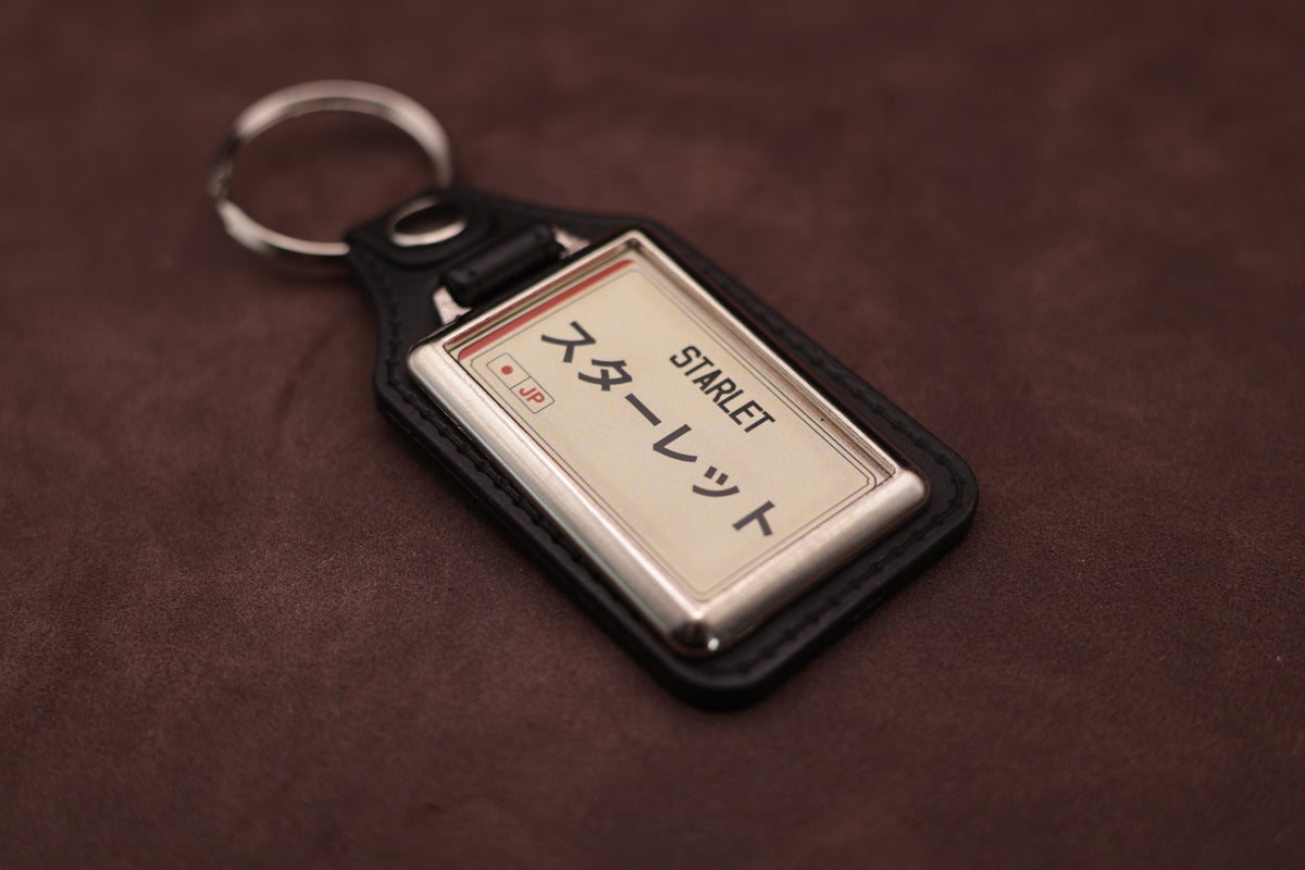 Toyota Starlet Katakana keyring angled with the split ring at upper left, showing the printed insert and chromed frame