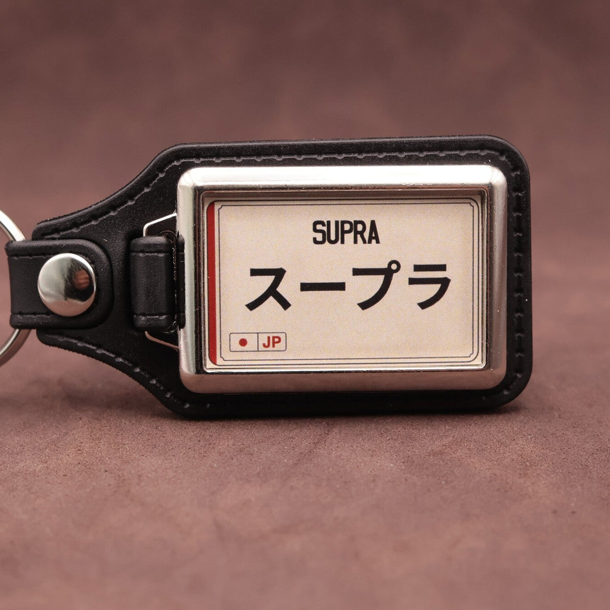 Toyota Supra keyring with Japanese katakana and model lettering on a cream plate-inspired insert