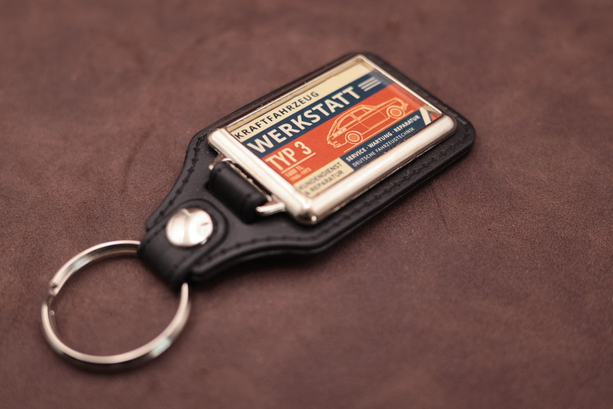 Volkswagen Type 3 Fastback Werkstatt keyring angled with the split ring at lower left, showing the printed label and black leatherette fob