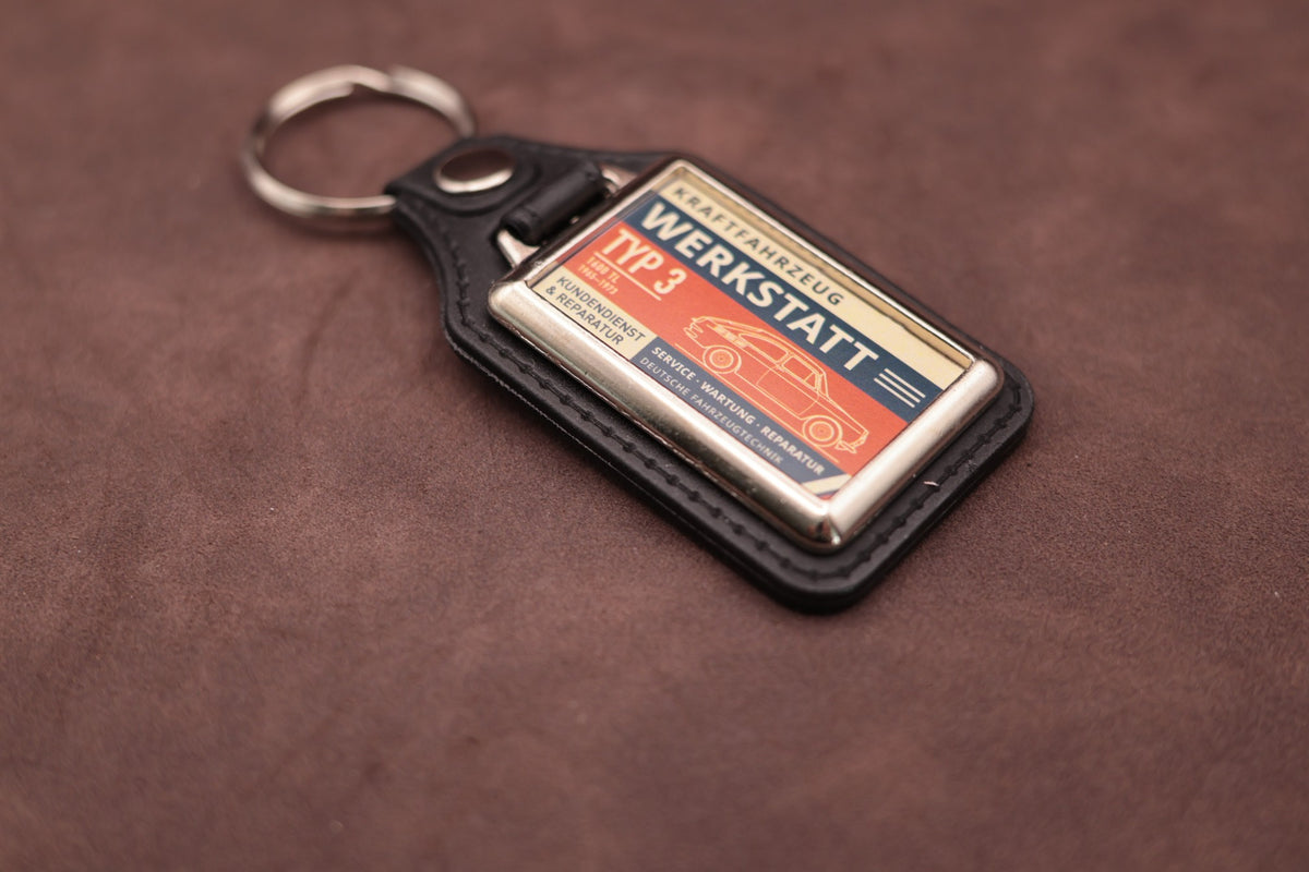 Volkswagen Type 3 Fastback Werkstatt keyring angled with the split ring at upper left, showing the printed label and chromed frame
